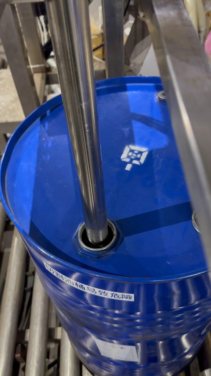 Stainless filling nozzle in a drum on the roller conveyor